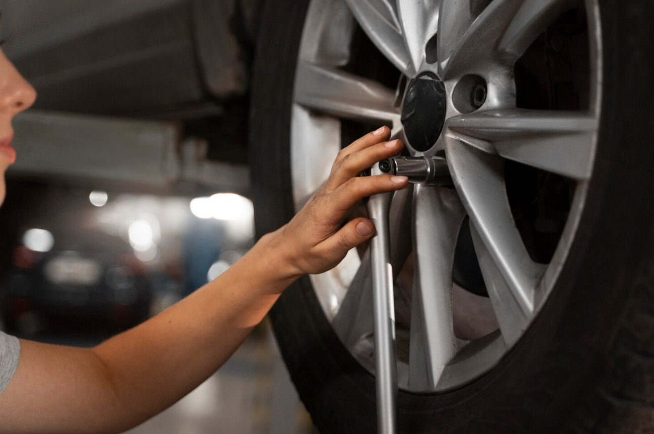Wrench positioned on a wheel fastener with the tire still resting on pavement